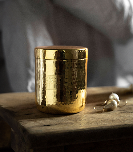 Gold textured container on a wooden surface with garlic bulbs