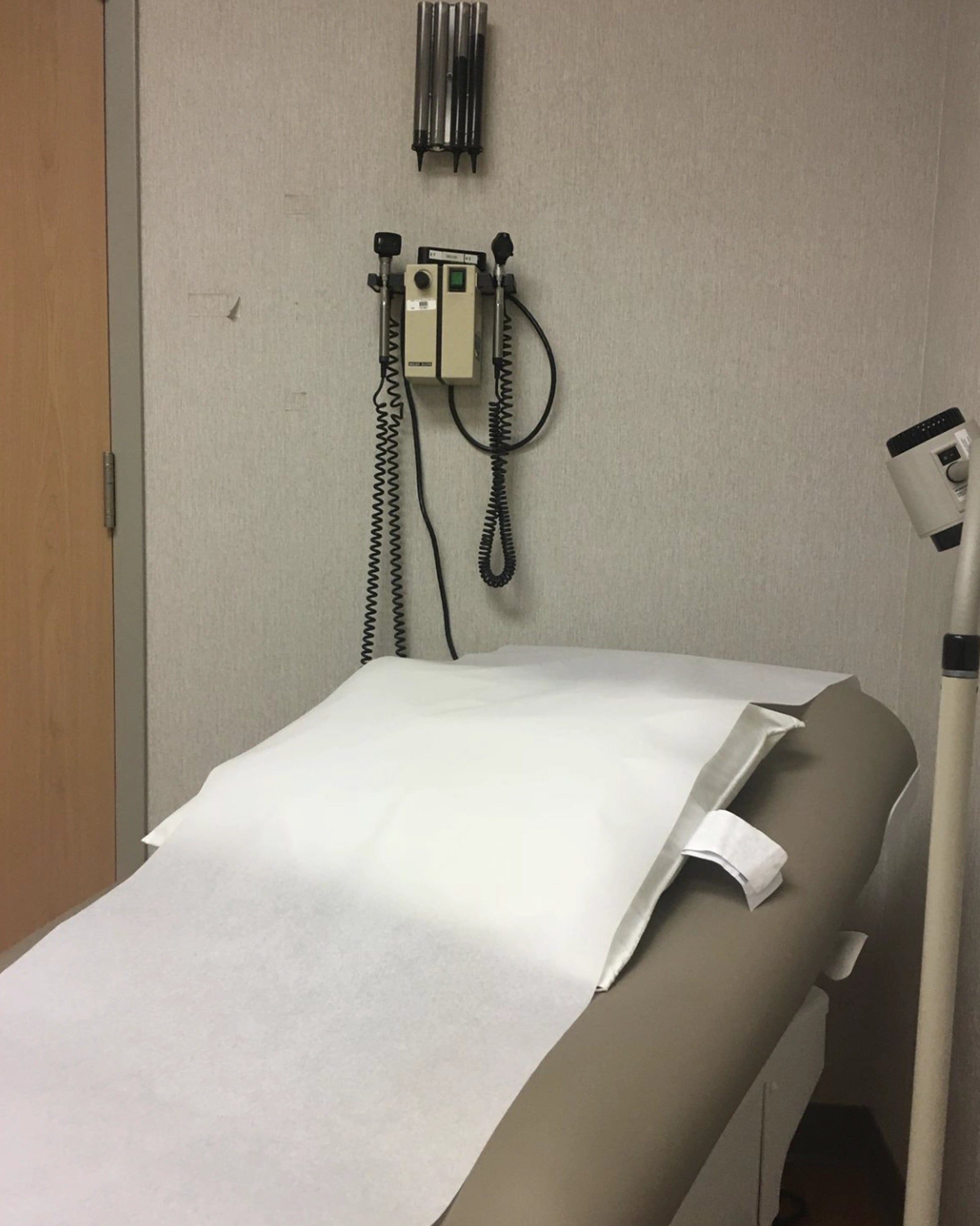 Medical examination table with a stethoscope and blood pressure monitor in a room.