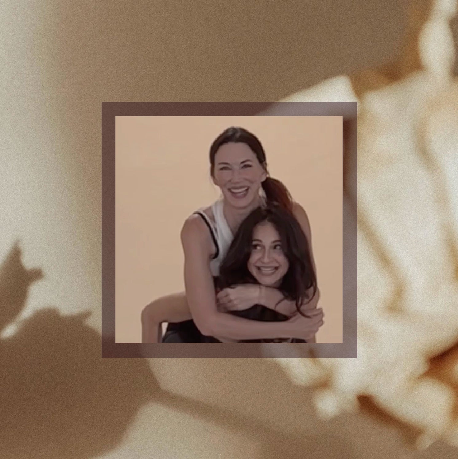 Two women (the cofounders Meg and Dr Meg) smiling and embracing in a warm hug against a soft beige background, displayed in a framed portrait style, the female founders behind Good Kitty.