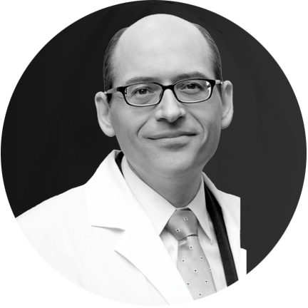 Black and white portrait of a person wearing glasses and a white coat.