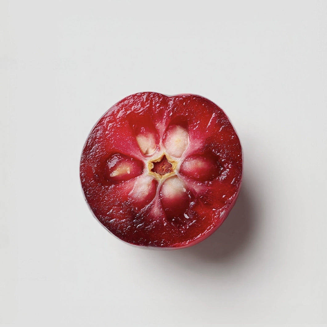 Halved red fruit with a white center on a light gray background