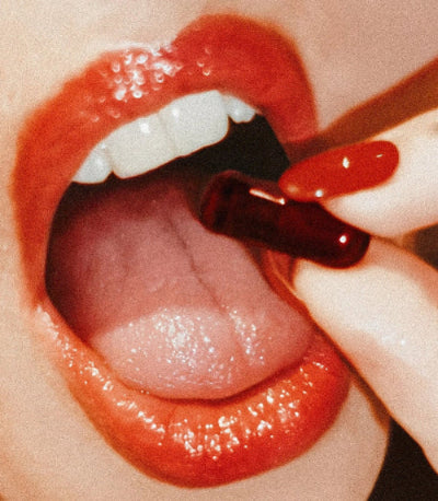 Close-up of glossy red lips with a UTI biome Shield capsule being placed on the tongue, styled with a vintage aesthetic. This is an artistic close-up image of lips/mouth with a pill, with text overlay that reads "non-antibiotic uti prevention" and a subheading "Powered by D-mannose, PACs, Zinc, and Vitamin D3 in one revolutionary pill." There's an "our science" button at the bottom.