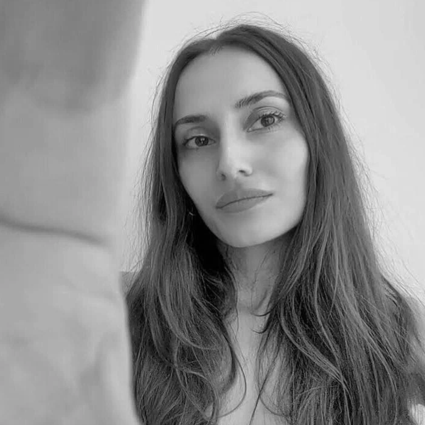 Black-and-white portrait of a woman with long hair and neutral expression.