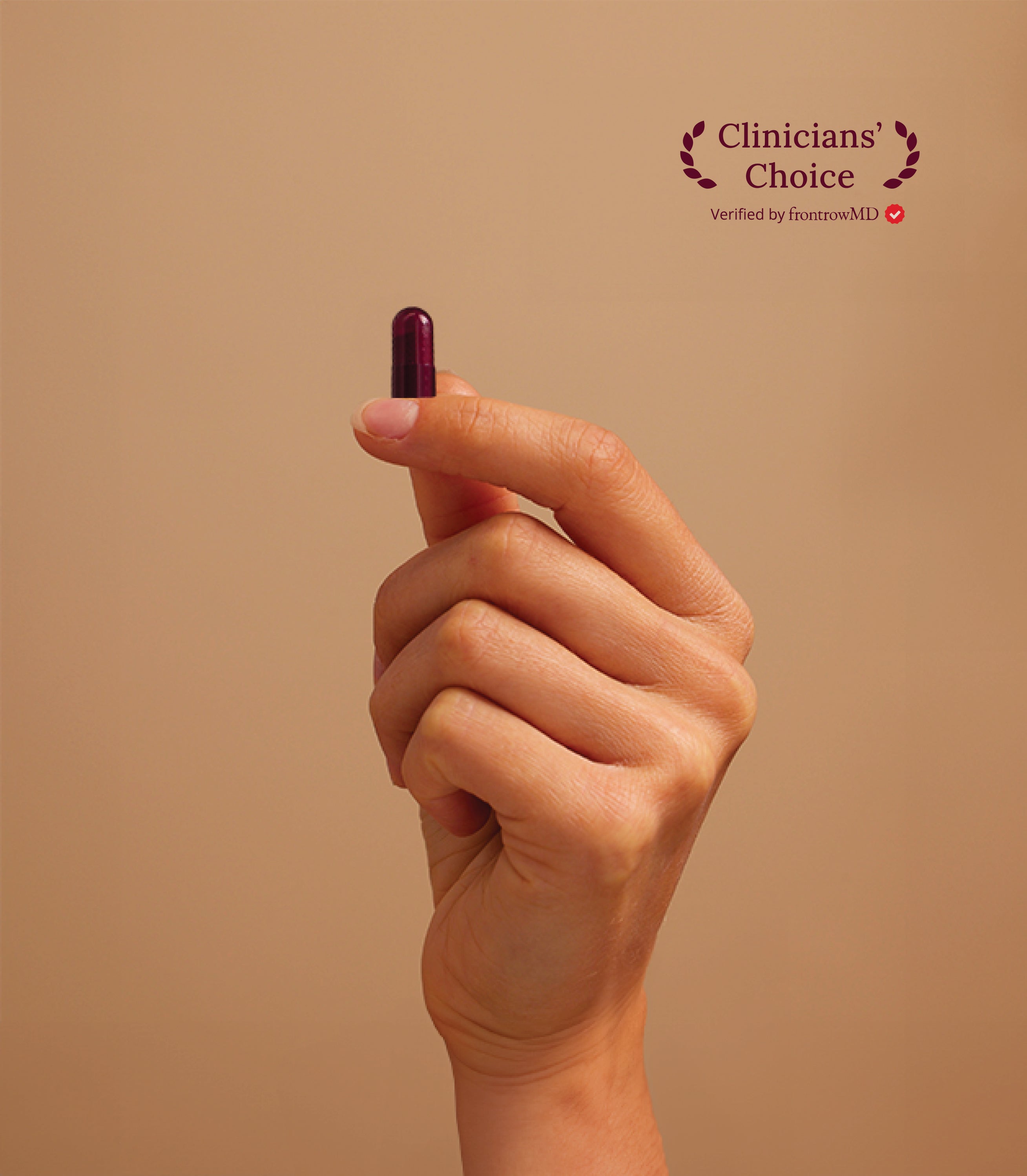Hand holding a purple pill against a beige background with 'Clinicians' Choice' text. This image shows a hand holding UTI biome Shield capsule or pill between the thumb and index finger. The background is a neutral beige color, creating a minimalist, clean presentation.
