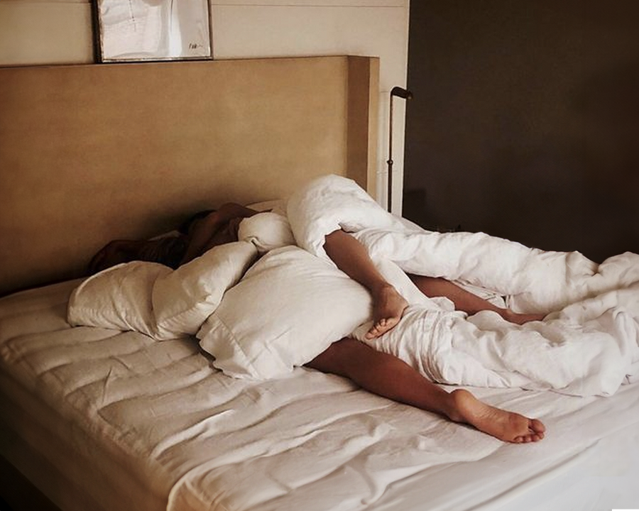 Couple resting in bed in a softly lit bedroom.