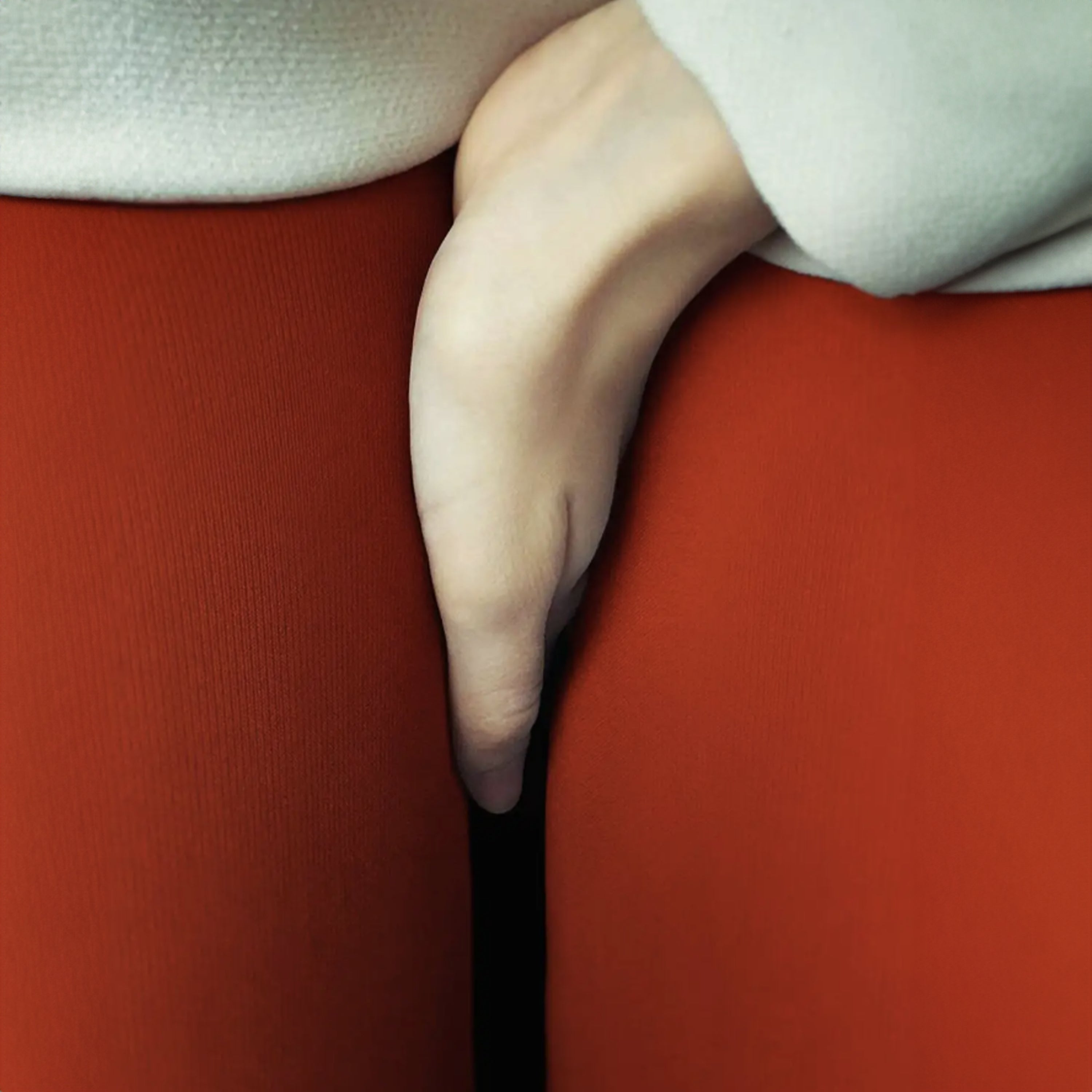 Close-up of a hand resting on a red surface with a blurred background