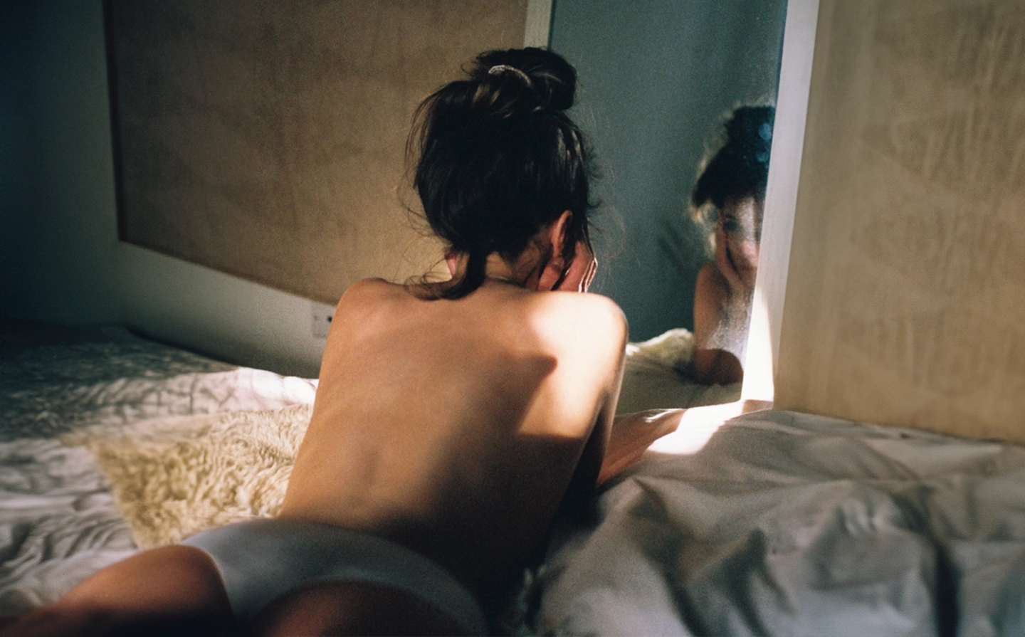 Woman with her back to the camera sitting on a bed with 'BEHIND THE BRAND' and 'we did it for womankind' text overlay. The Good Kitty logo appears at the top with a tagline 'we did it for us. we did it for sex.' below, highlighting the brand's mission.
