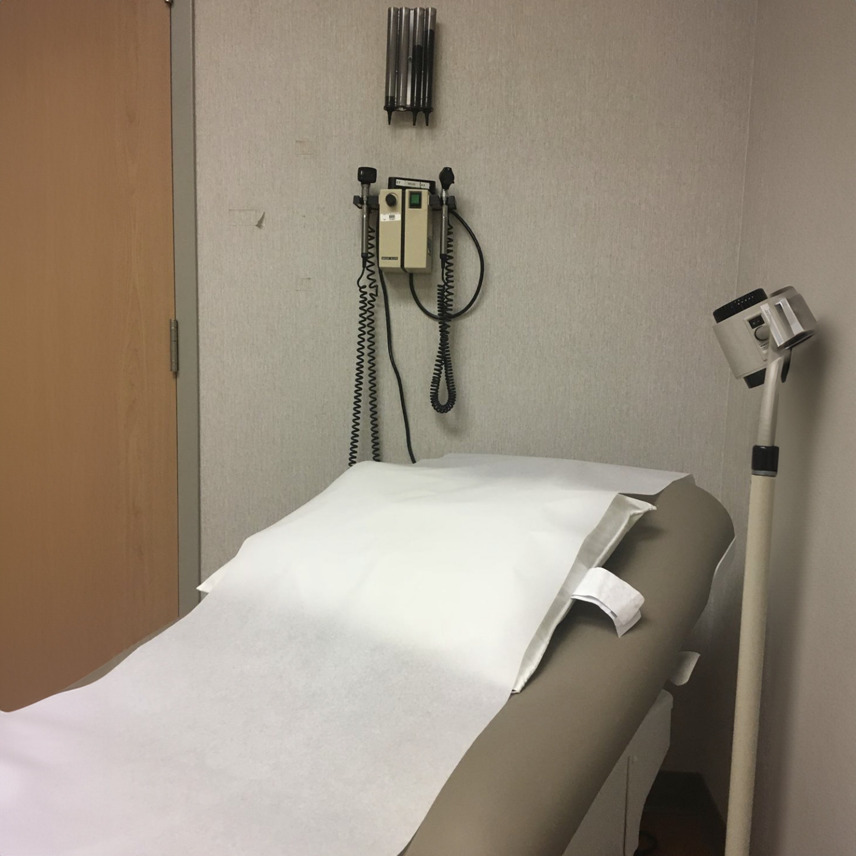 Medical examination table in a clinical setting with medical equipment on the wall.